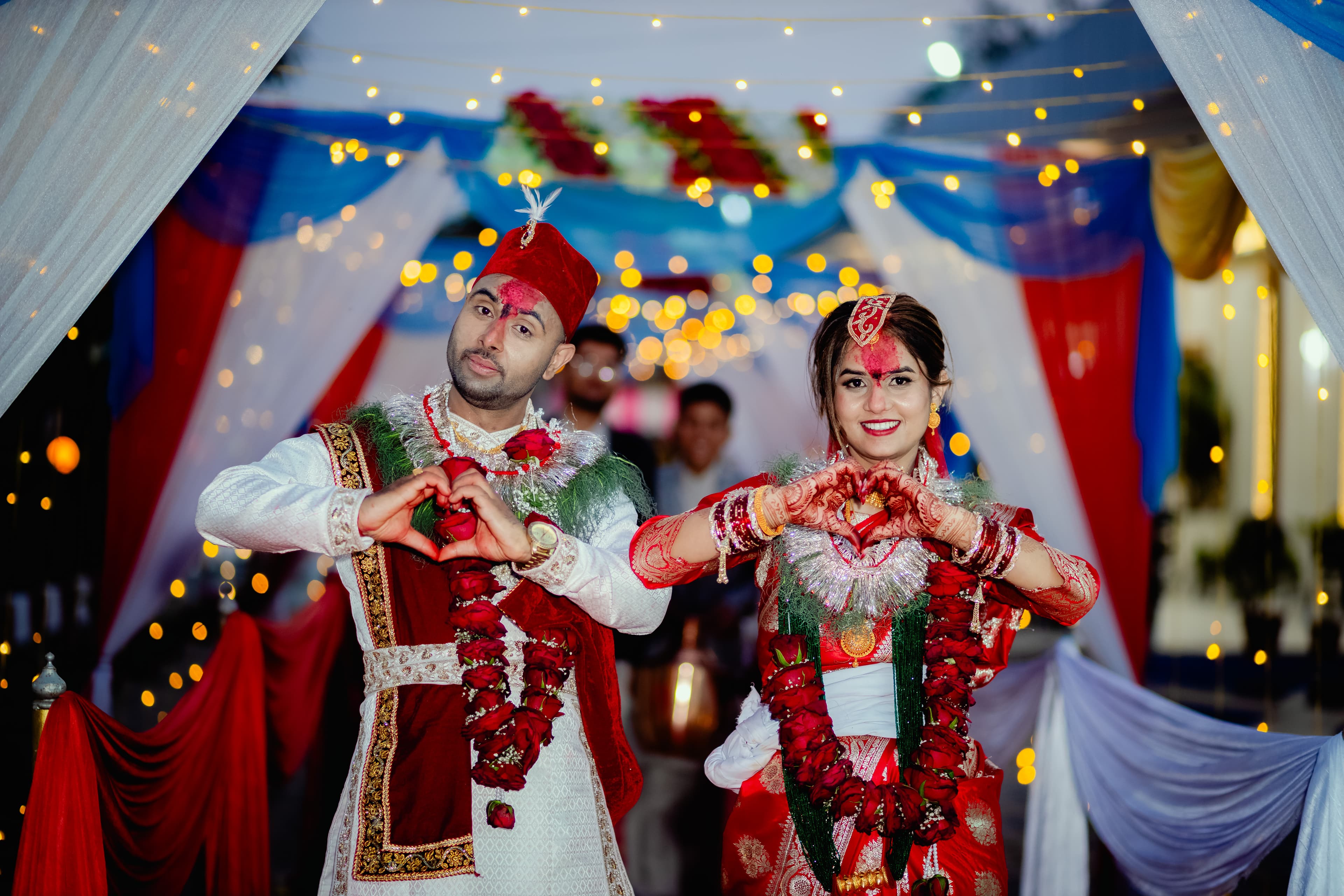 Wedding couple making heart pose with fairy lights